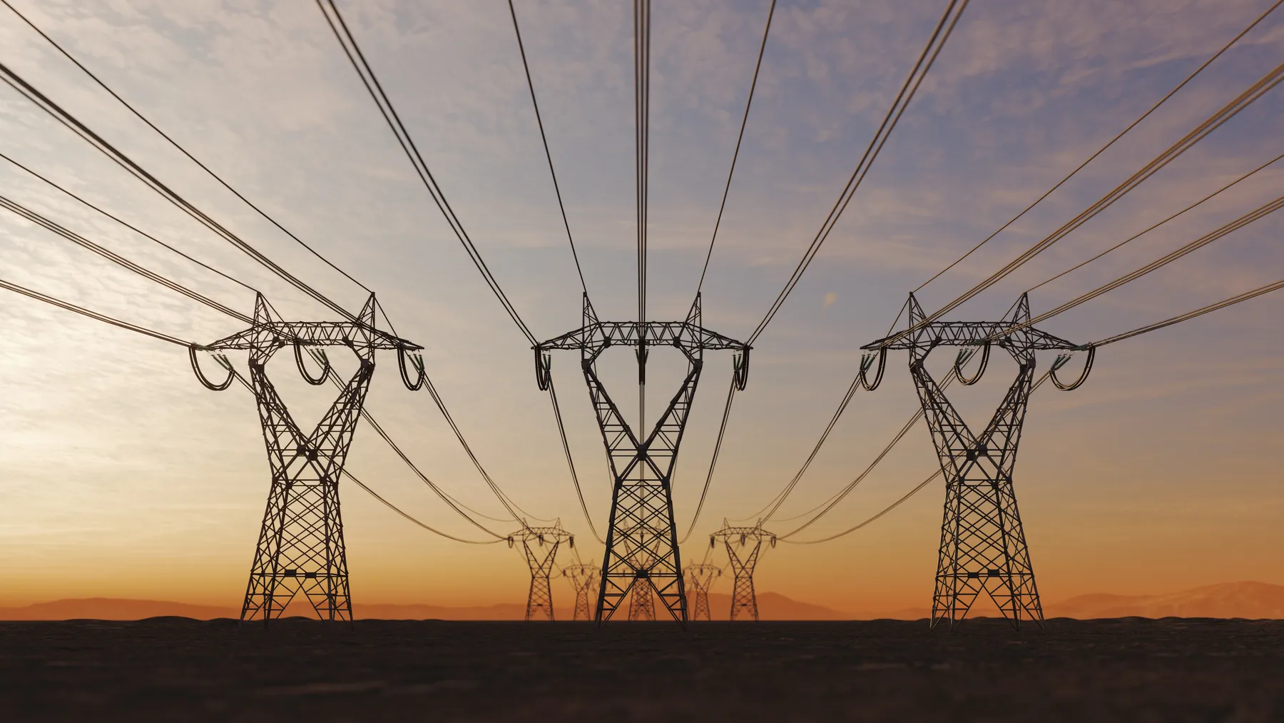 The silhouette of a high voltage power line line towers during sunset.