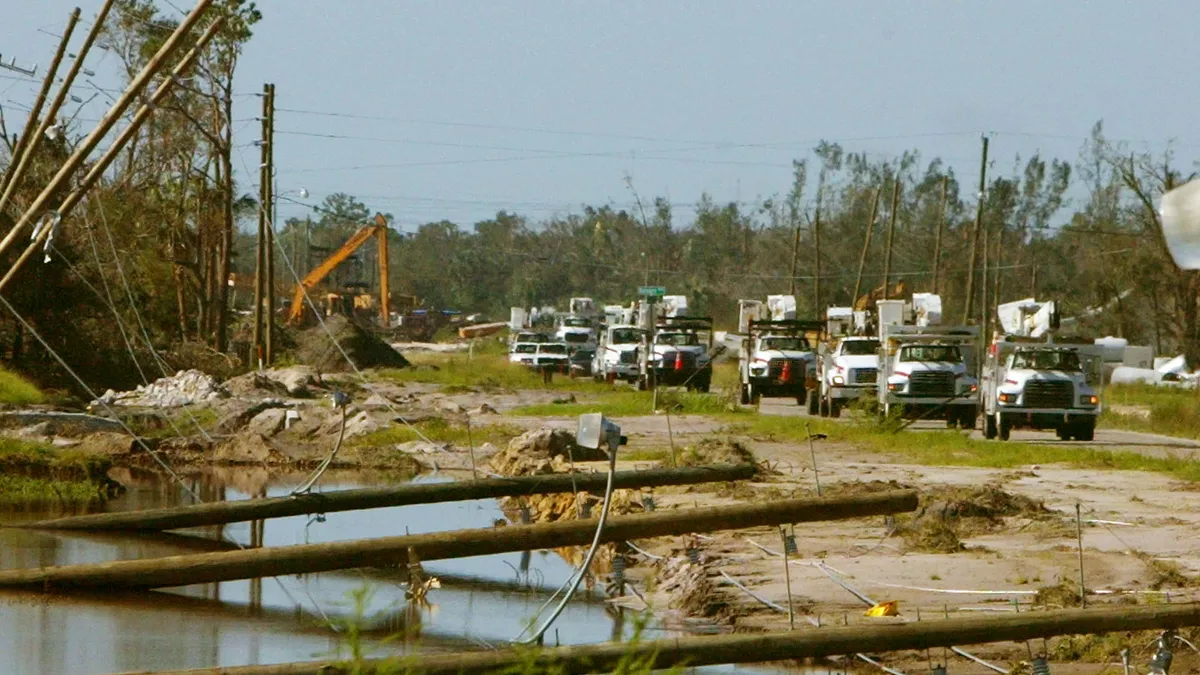 Utility maintenance trucks drive past downed power lines on their way to make repairs August 15, 2004 in Punta Gorda, Florida.