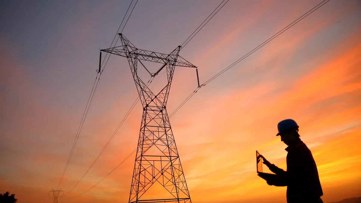 Electrical engineer while working laptop near a power line.