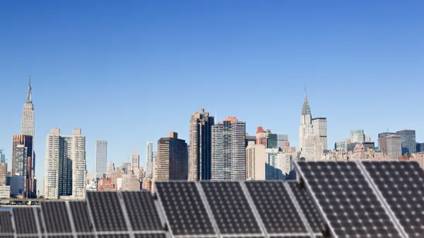 A rooftop solar installation against the backdrop of the Chrysler Building and the Empire State Building in midtown Manhattan.